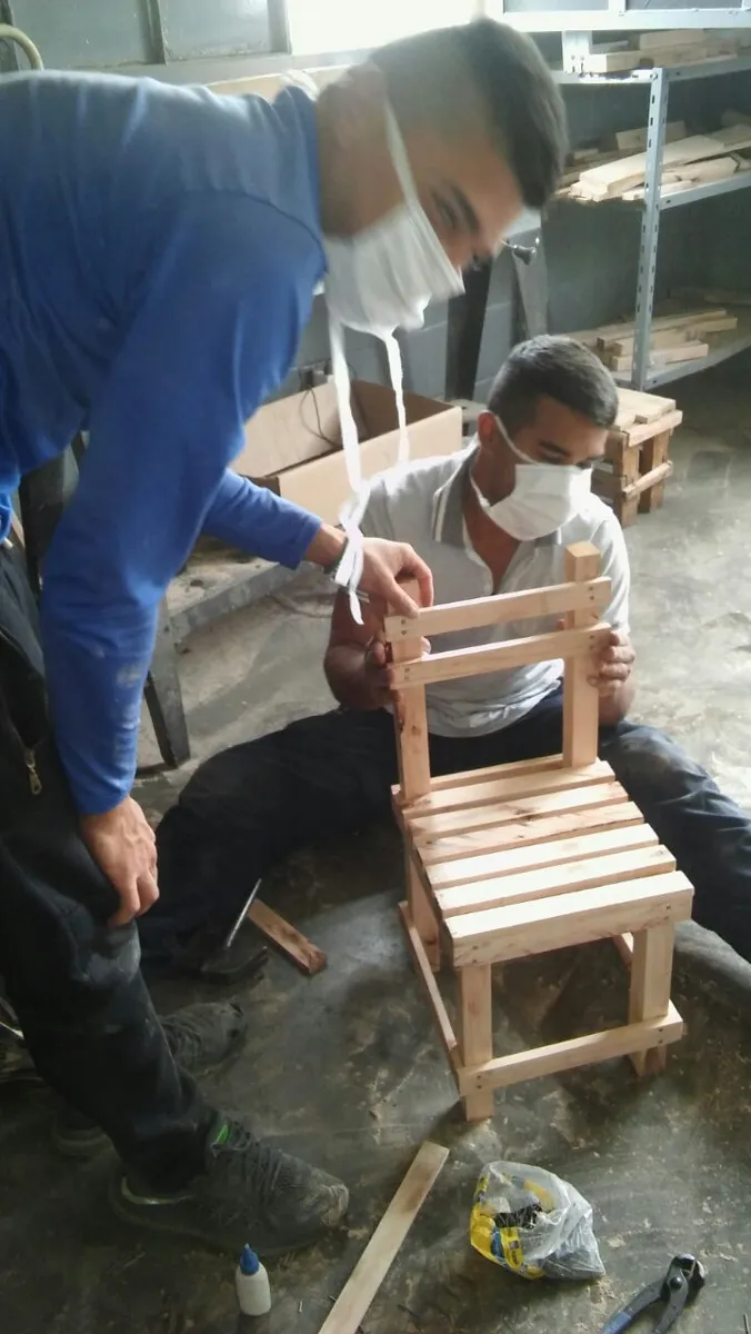 Dos participantes armando una silla de madera