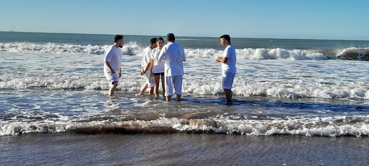 Pastores acompañan a una bautizada entre las olas